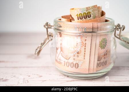 Thai Baht Banknoten in Gras Glas auf Holzhintergrund, Business-Sparen Finanzierung Investitionskonzept. Stockfoto