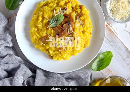 Traditionelles italienisches Risotto mit Pilzen, Safran und Parmesan auf Holzhintergrund. Draufsicht. Stockfoto