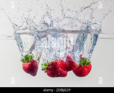 Reife Erdbeeren ins Wasser fallen Stockfoto