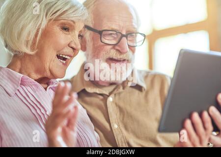 Nahaufnahme von glücklichen älteren Ehemann und Ehefrau mit digitalem Tablet und Chat während eines Videoanrufs zu Hause. Lifestyle-Konzept Stockfoto