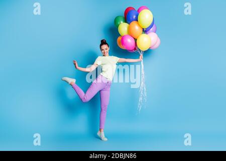 In voller Länge Körpergröße Foto von lustigen Mädchen halten Haufen Von bunten Luftballons lächelnd glücklich isoliert auf lebendiges Blau Farbiger Hintergrund Stockfoto