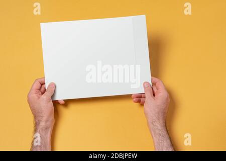 Männliche Hände mit einem A4-Papierumschlag, bearbeitbare Nachbau-Vorlage für Ihr Design, Auswahlpfad enthalten Stockfoto