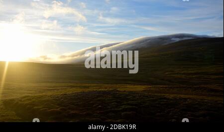 Eine Hochsommernacht in Island. Wolken treiben einen Berg hinunter. Contre-jour. Stockfoto