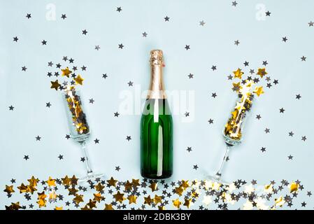 Champagner-Flasche und Flöten mit schwarzen und goldenen Sternen und Kreis Konfetti auf dem blauen Hintergrund. Weihnachten, Neujahr oder Geburtstag oder Hochzeit festlich c Stockfoto