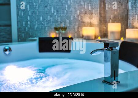 Blaues sprudelndes Wasser im Spa Jacuzzi Close-up Wasserhahn mit Kerzen auf dem Hintergrund, entspannen und Lifestyle Abstrakten Hintergrund mit blauen Lichtern dekoriert Stockfoto