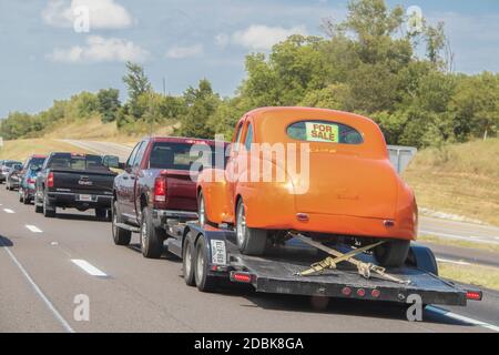 Aug 13 2019 Ft Worth USA Linie von Autos und LKW auf Autobahn - hinten zieht man Anhänger mit orange Oldtimer geschnallt auf mit für Verkauf Zeichen in zurück wi Stockfoto