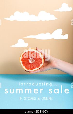 Beschnittene Ansicht der Frau hält saftige Hälfte der Grapefruit in der Nähe Sommer Verkauf, in den Geschäften und Online-Schriftzug auf beige und blau Stockfoto