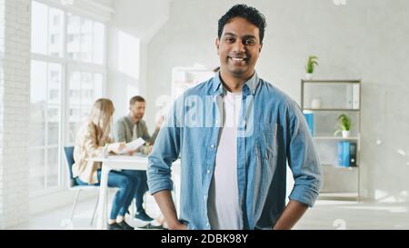 Indischer Mann smilling bei der Arbeit Porträt. Mann im Creative Office. Sonniger Tag bei der Arbeit im Büro. Stockfoto