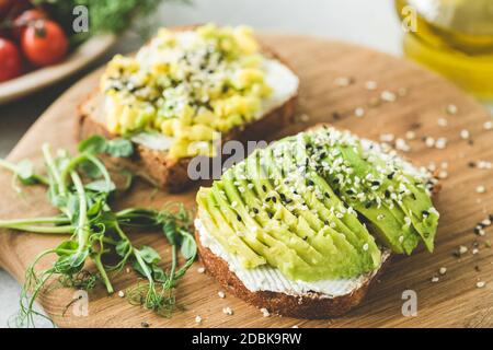 Avocado Toast mit Sesam auf Holzbrett. Gesunde Vorspeise, Snack oder Frühstück mit Avocado-Scheiben Stockfoto