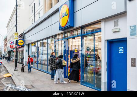 Kunden, die Schlange stehen, um den Lidl-Supermarkt in Kentish Town während der zweiten Sperre der Coronavirus-Pandemie in London, Großbritannien, zu betreten Stockfoto