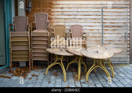 Gestapelte Tische und Stühle auf der Terrasse eines Restaurants, während der Sperre wegen der Coronavirus-Pandemie geschlossen, ausgewählter Fokus Stockfoto