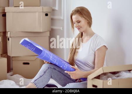 Mädchen sitzt zwischen Boxen macht Marken auf dem Plan der Wohnung Stockfoto