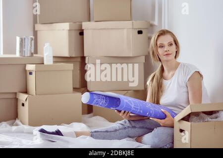 Mädchen sitzt zwischen Boxen macht Marken auf dem Plan der Wohnung Stockfoto