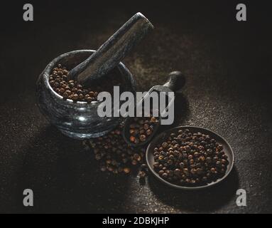 Getrocknete schwarze Pfefferkörner Konzept auf dunklem Hintergrund Stockfoto