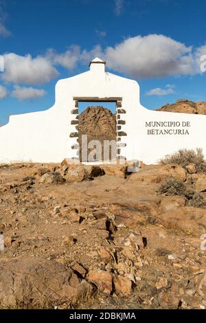 Typisches Gemeindeschild (weißes Bogentor) in der Nähe von Betancuria Dorf mit Wüste Berglandschaft im Hintergrund, Fuerteventura, Kanarische Inseln, S Stockfoto