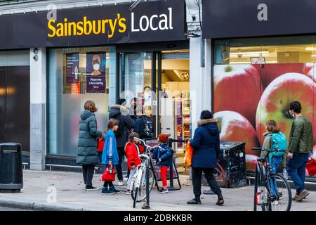 Kunden, die in Sainsbury's Local in Fortess Road Schlange stehen, während der zweiten Blockade der Coronavirus-Pandemie, Tufnell Park, London, Großbritannien Stockfoto