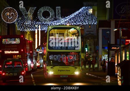 Brighton Sussex UK 17. November 2020 - Busse mit festlichen Botschaften, die sich in den Fenstern spiegeln, passieren unter den Weihnachtslichtern in North Street , Brighton und verleihen dem Coronavirus COVID-19 Sperrbeschränkungen in England etwas Glanz : Credit Simon Dack / Alamy Live News Stockfoto