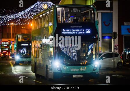 Brighton Sussex UK 17. November 2020 - Busse mit festlichen Botschaften, die sich in den Fenstern spiegeln, passieren unter den Weihnachtslichtern in North Street , Brighton und verleihen dem Coronavirus COVID-19 Sperrbeschränkungen in England etwas Glanz : Credit Simon Dack / Alamy Live News Stockfoto