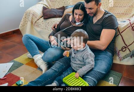 Schwangere Frau und Mann suchen Tablette, während Sohn spielt Stockfoto