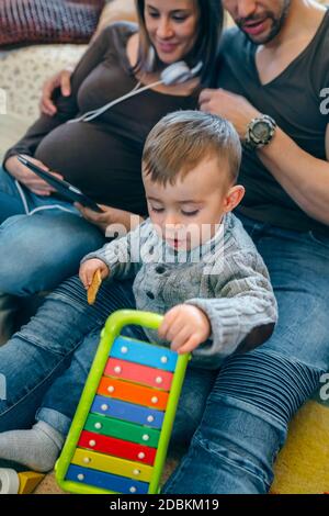 Schwangere Frau und Mann suchen Tablette, während Sohn spielt Stockfoto