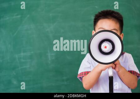 Zurück zur Schule. Asiatisch lustig niedlich kleine Kind junge Kindergarten Vorschule in Schüler Uniform sprechen durch Megaphon gegen auf grüne Schule Blackbo Stockfoto