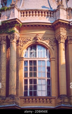 Bogenfenster mit einem schönen alten Stein Relief Zierdekoration, Porträt, florale Elemente und Säulen. Vajdahunyad Schloss im Stadtpark Stockfoto