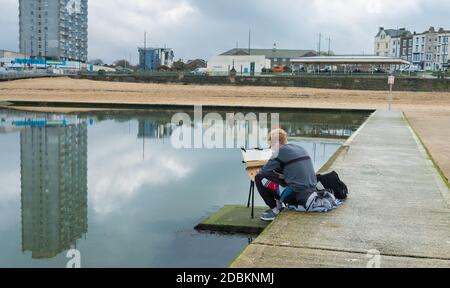 Mann malt auf dem Gezeitenpool am Strand von Marine Terrace, Margate, Kent Stockfoto