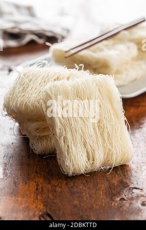 Ungekochte weiße Reisnudeln auf Holztisch. Stockfoto