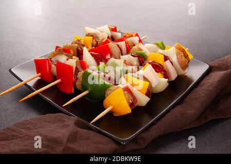 Hühnchen-Kebab. Rohes Fleisch und Gemüse auf Spieße, fertig zum Grillen auf schwarzem Hintergrund. Stockfoto