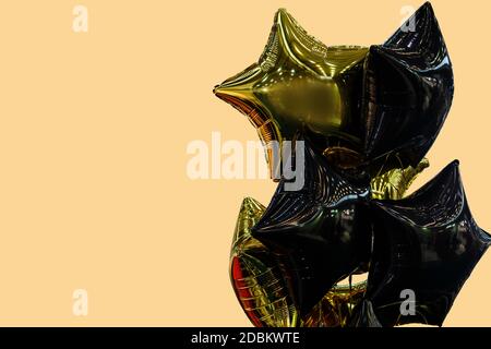 Eine Gruppe von schwarzen und goldenen Luftballons auf einem beigen Hintergrund mit Kopierbereich Stockfoto