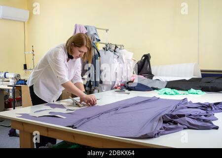 Modedesigner schneidet auf die Materialdetails von Kleidung in der Werkstatt Stockfoto