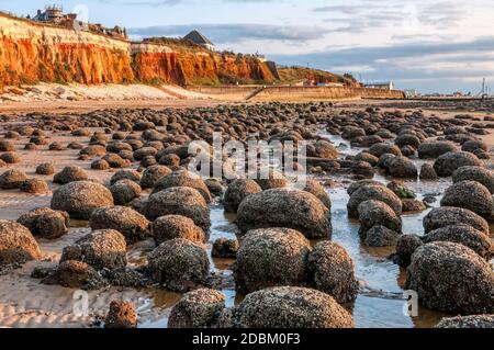 Überreste einer wellenförmigen Plattform vor den berühmten rot-weiß gestreiften Klippen in der Küstenstadt Hunstanton an der Ostküste in Norfolk. Stockfoto