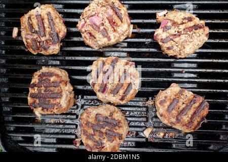 Blick von oben auf hausgemachte Burger auf einem Gas BBQ im Freien Stockfoto