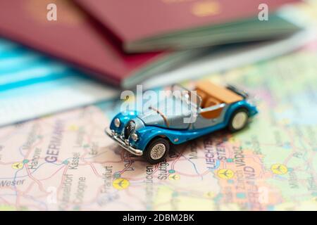 Spielzeug eines Autos, medizinische Maske und Reisepass auf der Europakarte. Stockfoto