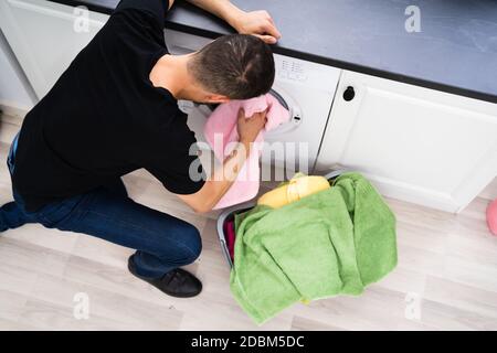Mann Lädt Kleidung In Waschmaschine In Der Küche Stockfoto