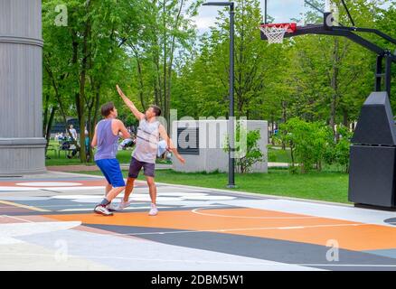 Sankt Petersburg, Russland. Juli 28, 2020. Zwei junge Erwachsene Männer spielen Basketball auf einem Streetball-Platz in einem Stadtpark. Gesunder Lebensstil, aktive Freizeit. Stockfoto