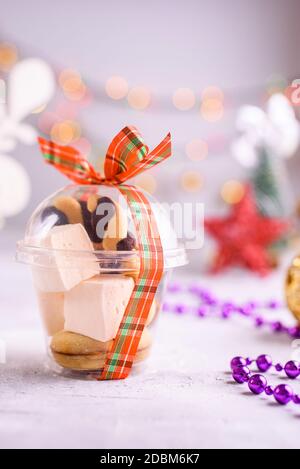 Box mit Satinbändern und leckeren Leckereien für Neujahr und Weihnachten. Neujahrsdesserts auf hellem Hintergrund. Frohe weihnachten Stockfoto