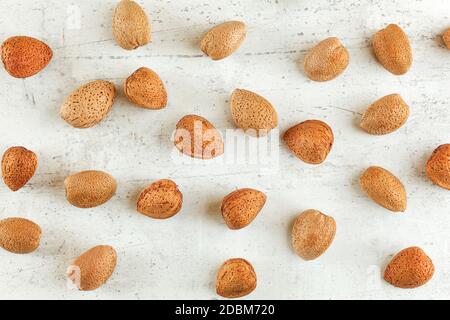 Draufsicht, ganze Mandeln in Schale auf weißem Steinbrett. Stockfoto