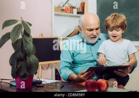 Schüler und Nachhilfe Bildungskonzept. Vater und Sohn. Bildungsprozess. Lehrertag. Glücklicher netter Enkel und Großvater sitzen an einem Schreibtisch Stockfoto