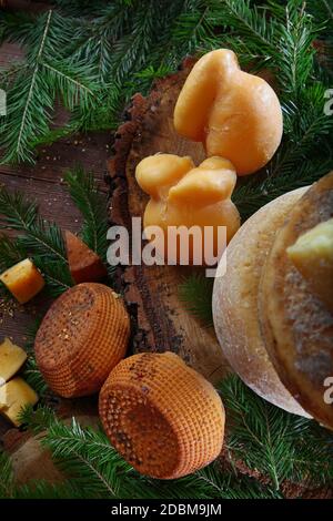 Große Stücke von hartem und geräuchertem Käse mit Tannenzweigen auf einem hölzernen Hintergrund. Blick von oben. Stockfoto