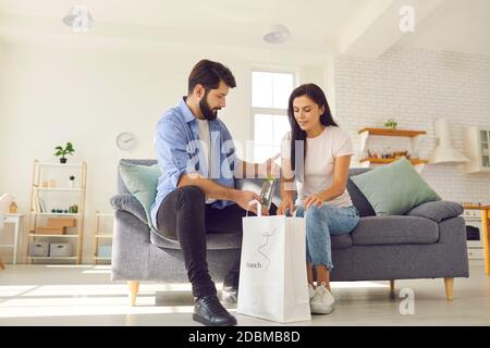 Junges Paar, das Beutel mit gesunden Speisen und Getränken auspackte, wurde geliefert Durch den Essensservice Stockfoto