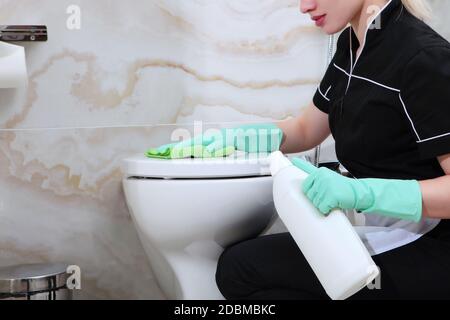 Eine junge Frau wäscht die Toilette im Marmorbad. Nicht erkennbares Foto. Reinigungsservice im Hotel oder zu Hause. Speicherplatz kopieren. Stockfoto