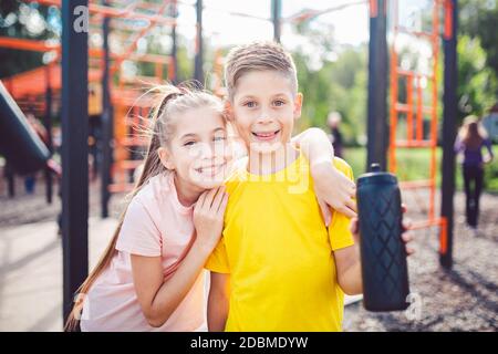 Sportliche Freunde. Bruder und Schwester stehen zusammen im Street City Gym. Kinder Athleten umarmen Lächeln während des Trainings. Zwillinge junge und Mädchen POS Stockfoto
