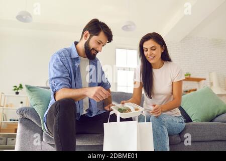 Junge lächelndes Paar Auspacken online gesund verpackt Lebensmittel bestellen Lieferung zum Abendessen Stockfoto