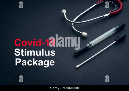COVID-19 oder CORONAVIRUS STIMULUS-PAKET Text mit Stethoskop und medizinischem Tupfer auf schwarzem Hintergrund. Covid-19 oder Coronavirus Konzept. Stockfoto