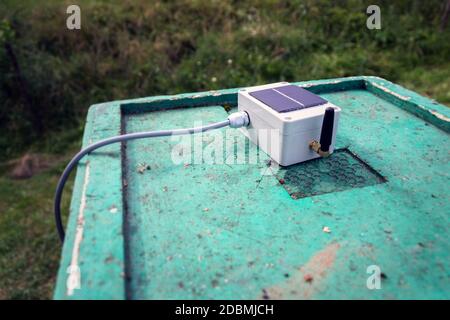 Weißer Sender mit kleinem Solarpanel und Bienen-Monitoring-System auf grünem Bienenstock aus Holz, intelligente Technologie iot-Anwendung Stockfoto