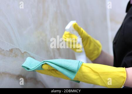 Reinigung im Badezimmer eines teuren Hotels oder zu Hause. Marmorfliesen an den Wänden. Nicht erkennbares Foto. Nur Hand. Speicherplatz kopieren. Stockfoto