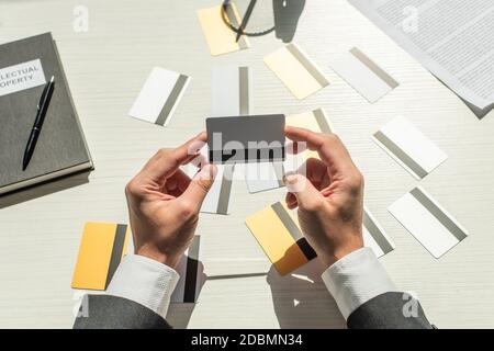 Beschnittene Ansicht des Geschäftsmannes, der seine Kreditkarte in der Nähe von Notebook und hält Geschäftsdokument auf weißem strukturiertem Hintergrund Stockfoto