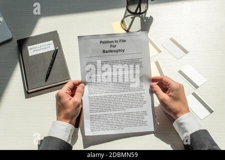 Beschnittene Ansicht des Geschäftsmannes, der Petition für Bankrott nahe Gutschrift hält Karten und Notizbuch auf weißem strukturiertem Hintergrund Stockfoto