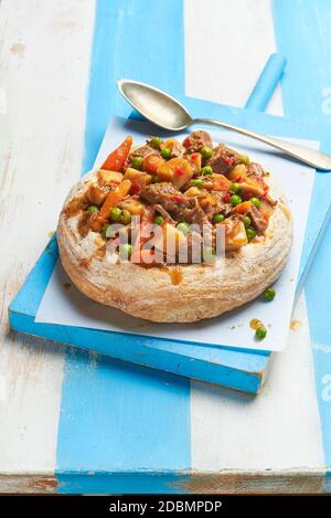 Gulasch serviert in einer Brotschale, einem traditionellen Rindfleischeintopf der ungarischen Küche. Stockfoto